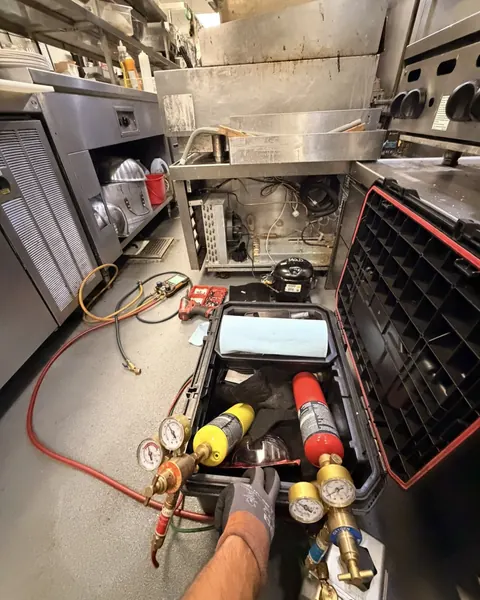 Refrigeration gauges and a torch kit set up on the floor of a restaurant kitchen
